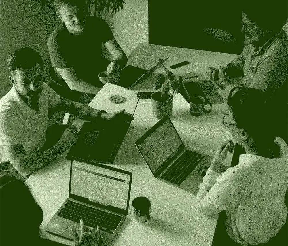 L'équipe de l'agence réunie autour d'une table de travail, ordinateurs portables ouverts.